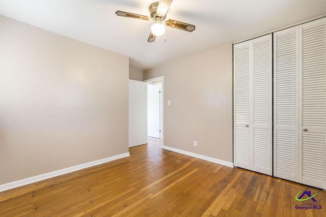 unfurnished bedroom with ceiling fan, a closet, wood finished floors, and baseboards