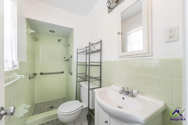 full bath with vanity, a shower stall, toilet, and tile walls