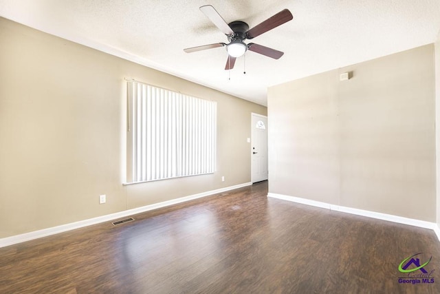 unfurnished room with ceiling fan, a textured ceiling, dark wood-type flooring, visible vents, and baseboards