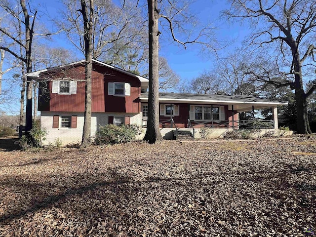 tri-level home featuring a porch, an attached carport, and brick siding