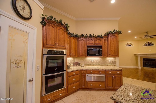 kitchen featuring double oven, black microwave, brown cabinetry, and a warming drawer