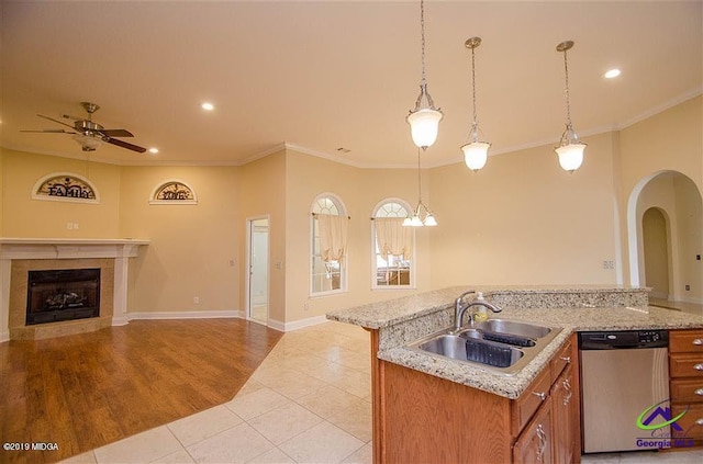 kitchen with open floor plan, stainless steel dishwasher, a fireplace, pendant lighting, and a sink