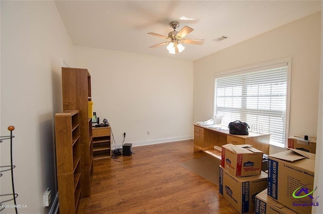 office space with ceiling fan, visible vents, baseboards, and wood finished floors