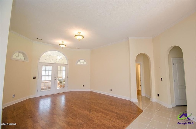 unfurnished room featuring baseboards, french doors, visible vents, and crown molding