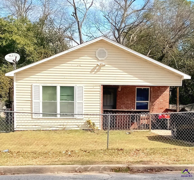 view of front of house with brick siding, a front yard, and fence private yard