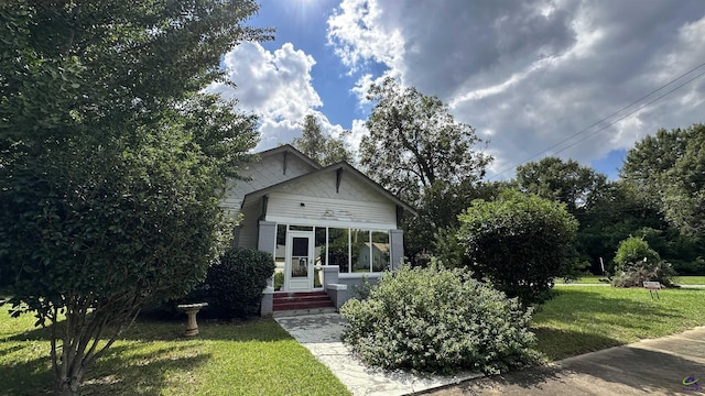 view of front facade featuring a sunroom and a front yard