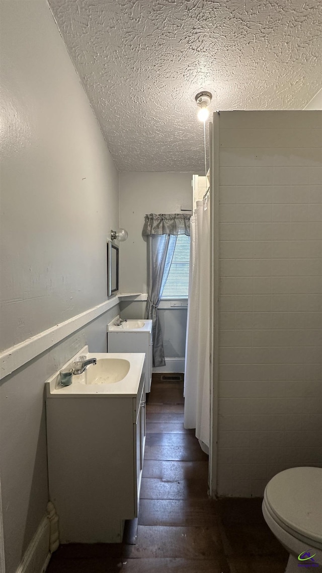 full bath featuring toilet, a textured ceiling, wood finished floors, and vanity