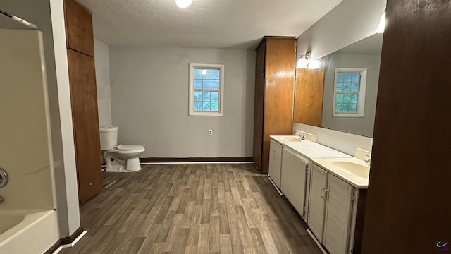 full bathroom featuring double vanity, a sink, toilet, and wood finished floors