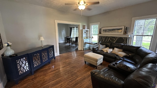 living area with a textured ceiling, ceiling fan, and dark wood-style flooring