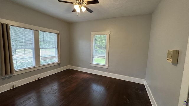 spare room featuring dark wood-style floors, a ceiling fan, and baseboards