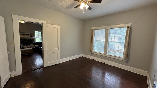 spare room with ceiling fan, a textured ceiling, baseboards, and dark wood-style flooring