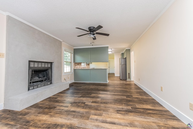 unfurnished living room with a fireplace with raised hearth, a textured ceiling, dark wood-type flooring, a ceiling fan, and ornamental molding