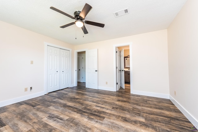 unfurnished bedroom featuring dark wood-style floors, a textured ceiling, visible vents, and baseboards