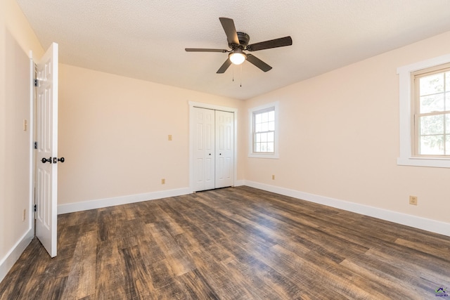 unfurnished bedroom featuring a textured ceiling, a closet, baseboards, and dark wood-type flooring