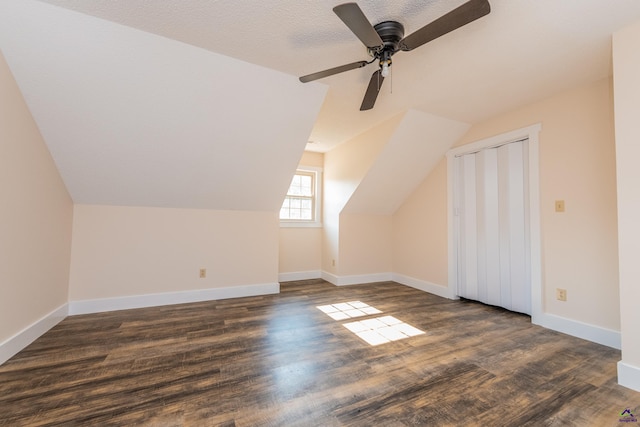 bonus room with dark wood-style floors, vaulted ceiling, and baseboards