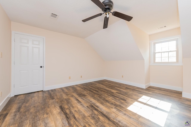 bonus room with dark wood-style floors, lofted ceiling, and visible vents