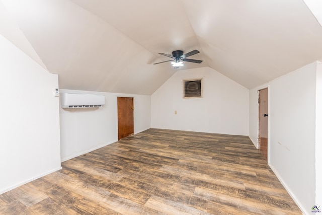 bonus room featuring lofted ceiling, dark wood-type flooring, a wall unit AC, and a ceiling fan