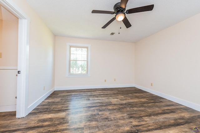 empty room featuring dark wood finished floors, visible vents, and baseboards