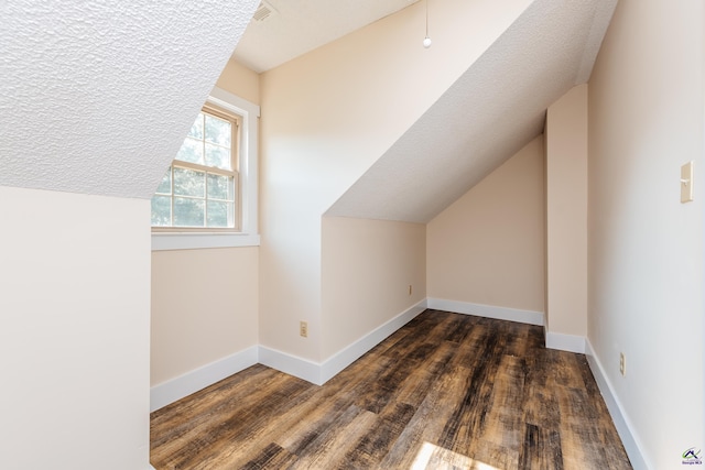 bonus room with lofted ceiling, a textured ceiling, dark wood finished floors, and baseboards