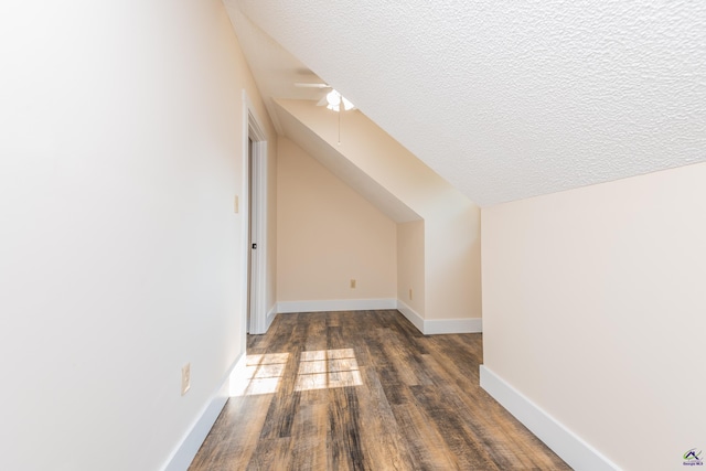 bonus room featuring vaulted ceiling, baseboards, dark wood-style flooring, and a textured ceiling