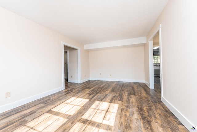 empty room featuring baseboards, dark wood finished floors, and a textured ceiling