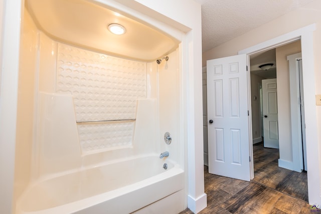 bathroom featuring bathtub / shower combination, baseboards, a textured ceiling, and wood finished floors