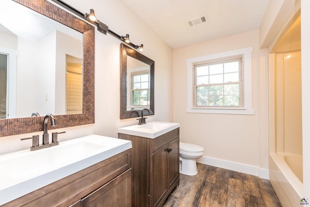 bathroom with wood finished floors, a sink, visible vents, and baseboards