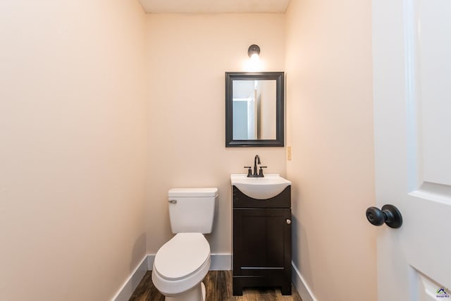 bathroom featuring toilet, vanity, baseboards, and wood finished floors