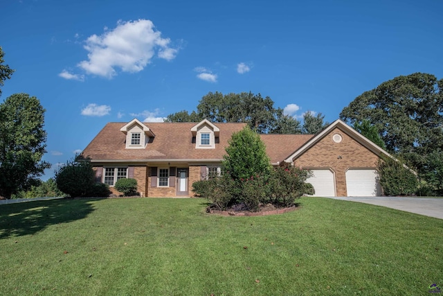 cape cod-style house with a front yard, concrete driveway, and brick siding