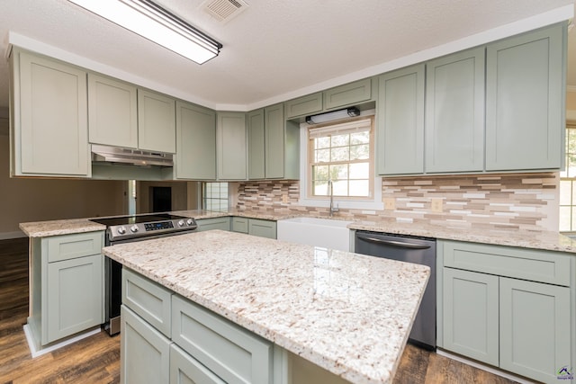 kitchen with visible vents, green cabinets, appliances with stainless steel finishes, a sink, and under cabinet range hood