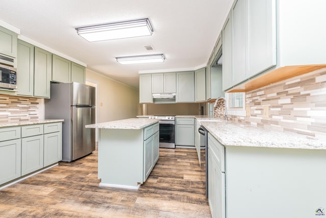 kitchen with visible vents, a kitchen island, appliances with stainless steel finishes, under cabinet range hood, and a sink