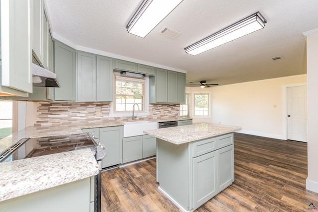 kitchen featuring visible vents, a kitchen island, light stone counters, stainless steel appliances, and a sink