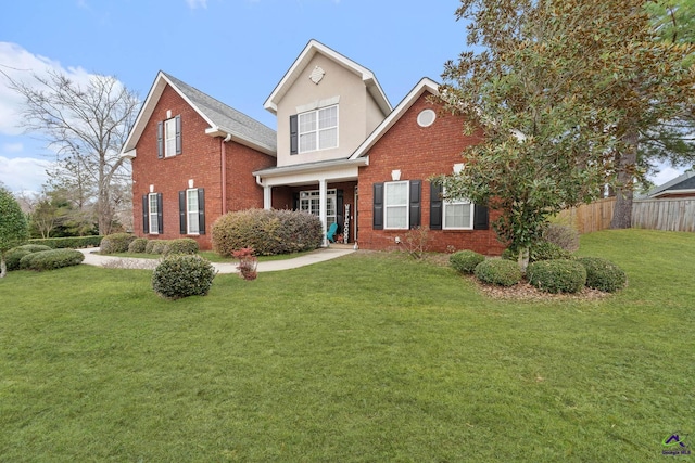 traditional-style home with brick siding, fence, and a front lawn