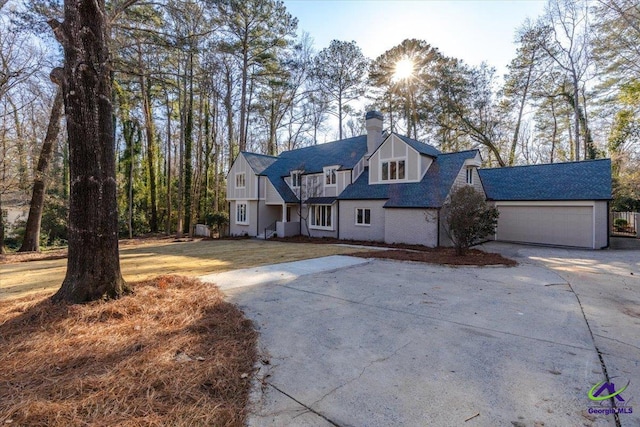 view of front facade with a garage, concrete driveway, and a chimney