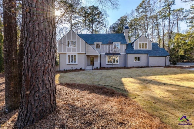 view of front of house featuring a front yard, brick siding, and a chimney