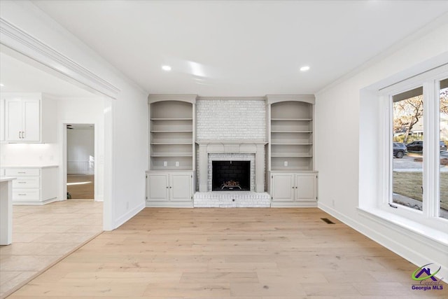 unfurnished living room featuring baseboards, light wood-style floors, a fireplace, and crown molding