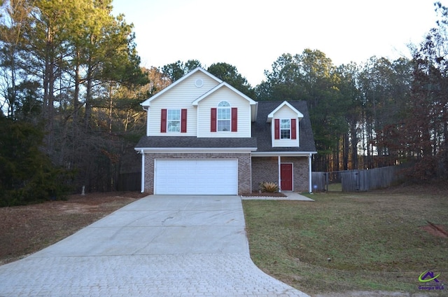 traditional home with driveway, an attached garage, fence, a front lawn, and brick siding