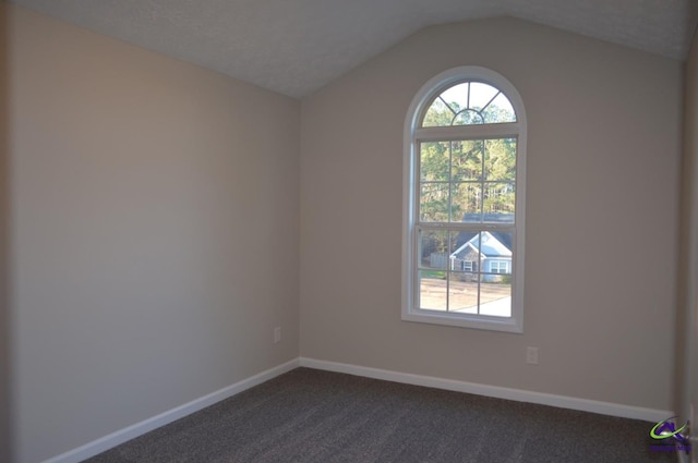 unfurnished room featuring a wealth of natural light, dark carpet, lofted ceiling, and baseboards