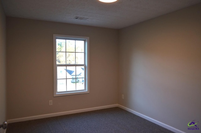 spare room featuring carpet, a textured ceiling, visible vents, and baseboards