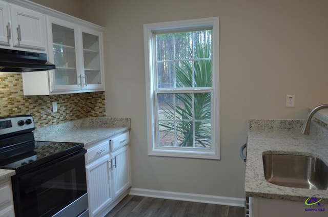 kitchen with under cabinet range hood, range with electric stovetop, a sink, white cabinets, and glass insert cabinets