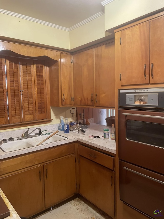 kitchen with light countertops, brown cabinetry, a sink, and crown molding