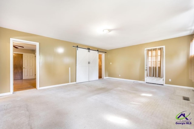 3271 Commodore Dr, Macon, GA 31211 - unfurnished bedroom with baseboards, carpet flooring, and a barn door