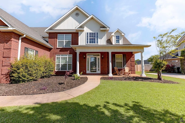 view of front of home with a porch, a front yard, and brick siding