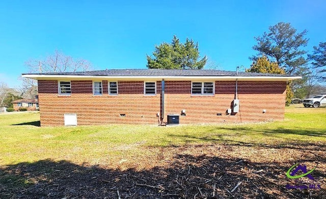 rear view of property featuring central AC, brick siding, and a lawn