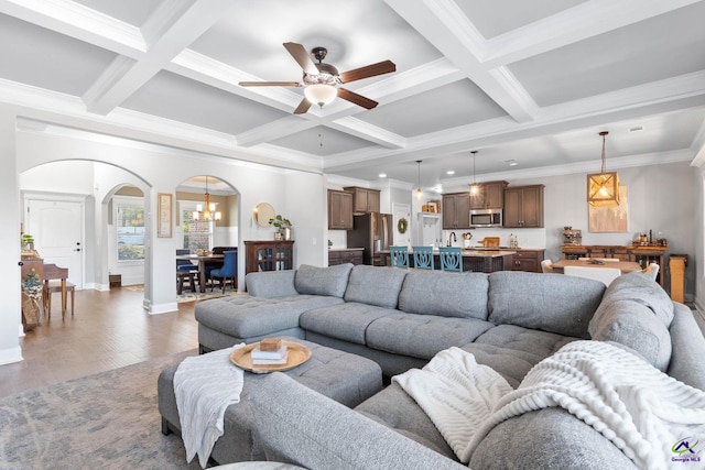 living area featuring arched walkways, coffered ceiling, wood finished floors, and beam ceiling