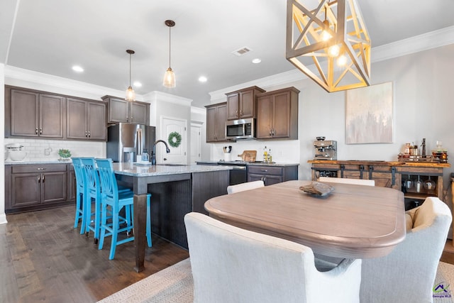 kitchen featuring visible vents, decorative backsplash, dark wood-style flooring, stainless steel appliances, and crown molding