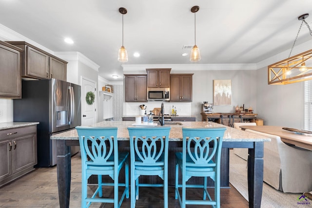 kitchen featuring appliances with stainless steel finishes, wood finished floors, a kitchen island with sink, and crown molding