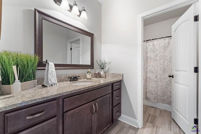 bathroom featuring curtained shower, vanity, and baseboards