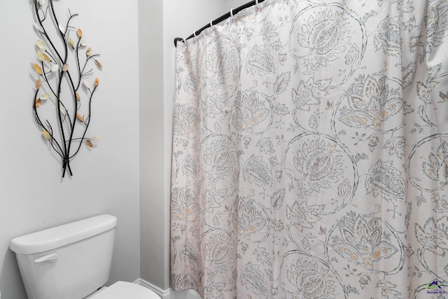 bathroom with a shower with shower curtain and toilet