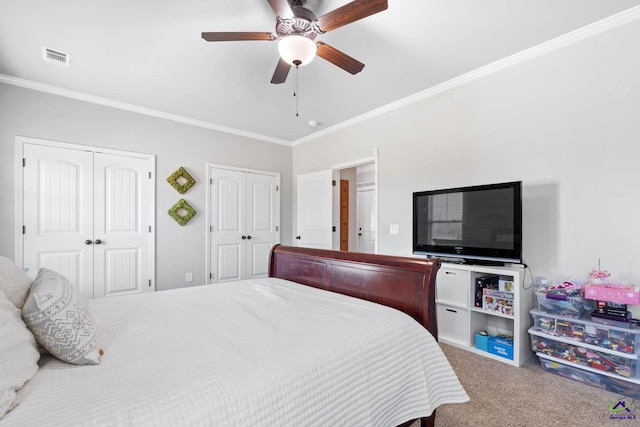 carpeted bedroom with a ceiling fan, visible vents, two closets, and ornamental molding